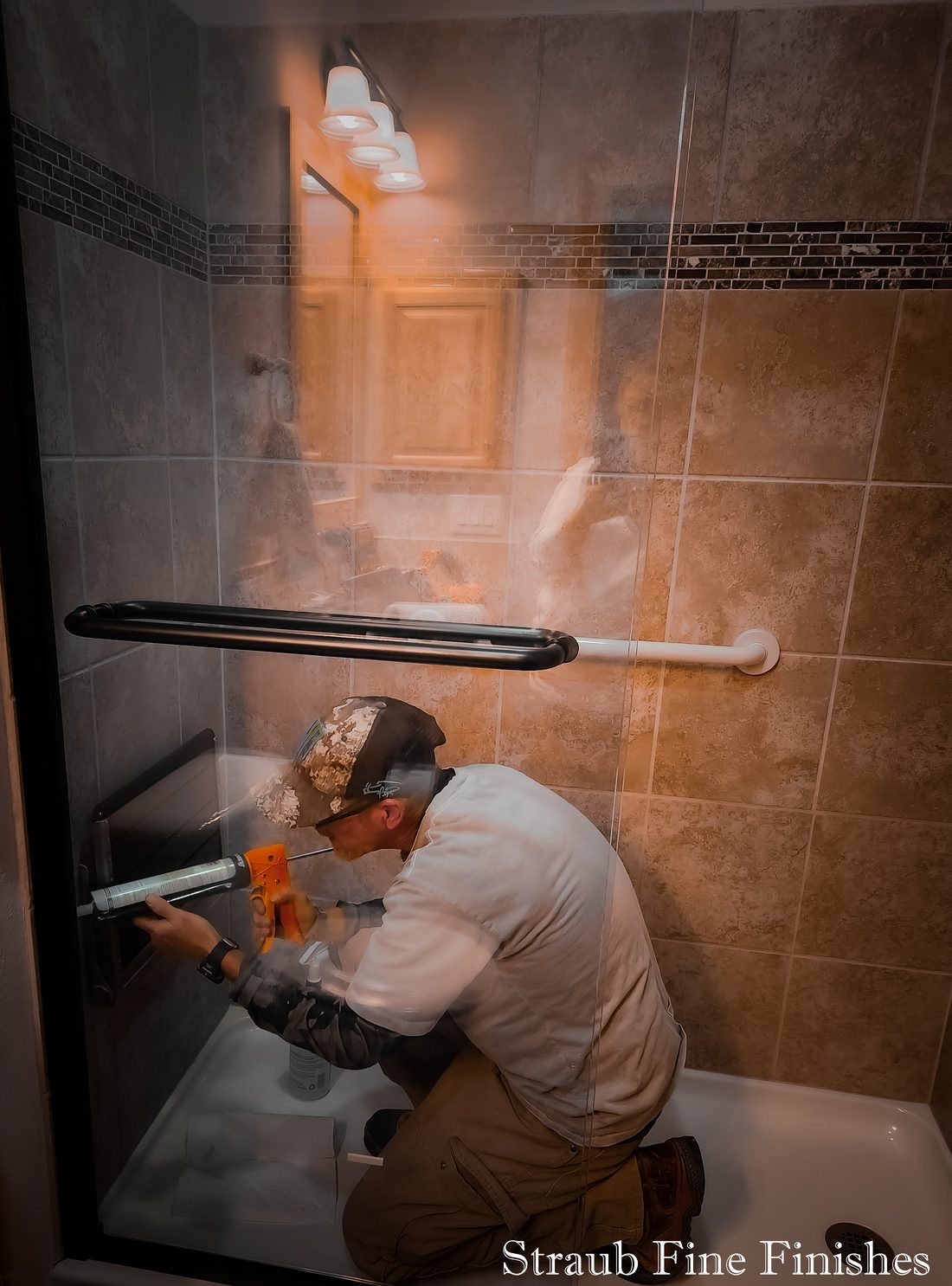 The owner of Straub Fine Finishes on the job, caulking a tiled shower in rural Colorado